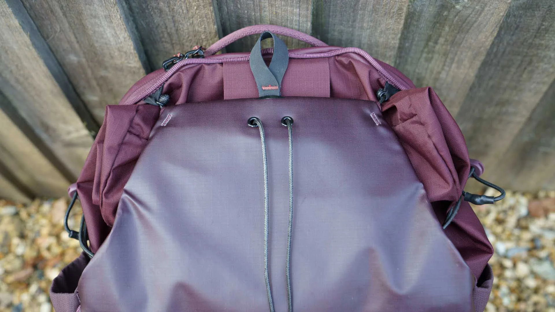 You need to pull the black loop at the top of this image to open the ‘kangaroo’ front pucj and roll-top section of the Peak Design Outdoor Backpack 25L. It’s closed by pulling the two ends of the drawstring while pushing the front pouch back towat=rds the main bag.