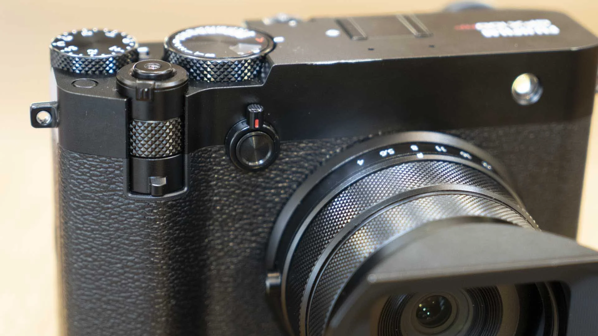  This image shows the stacked dial control on the front of the Fujifilm GFX100RF beneath the shutter button. The switch to the right with the small red mark is customisable but can be used to toggle through the teleconverter settings. 