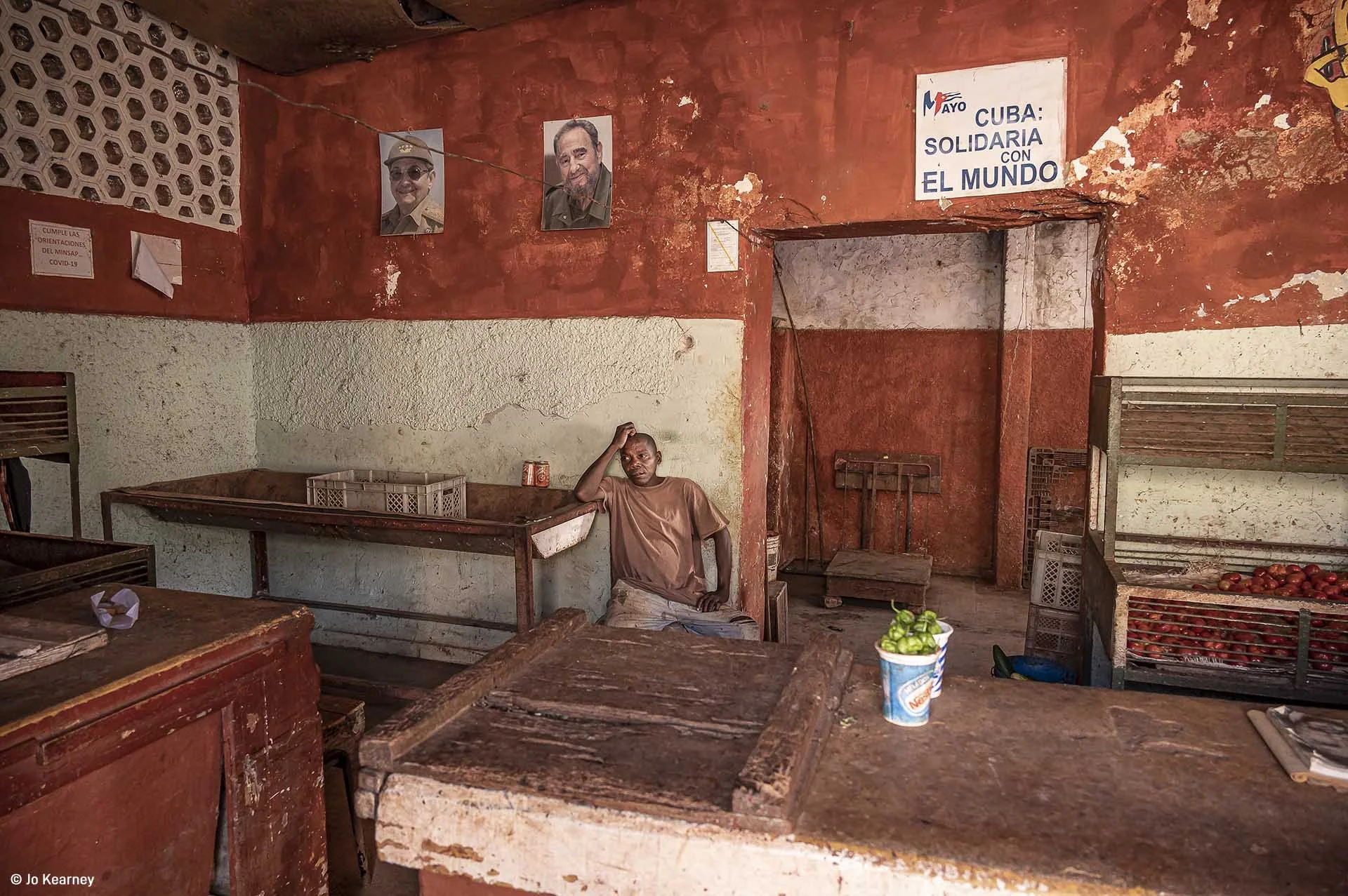  Image credit: Jo Kearney	Empty Shop, Cuba	A shopkeeper resting in a greengrocer's shop in Cuba. The state shops tend to be pretty empty. When food arrives there's a queue because they are subsidised by the government and so food is much cheaper than in the private stores. 
