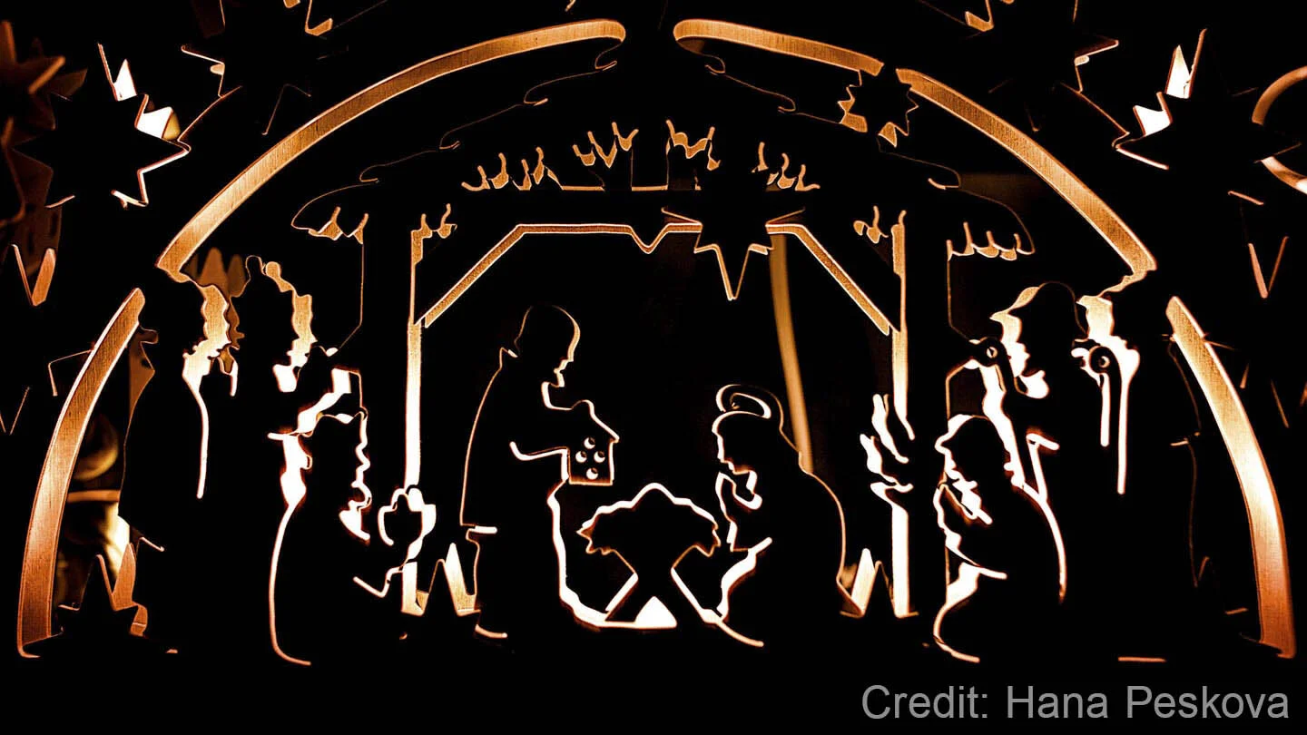 Silhouette of a nativity scene with figures like Mary, Joseph, baby Jesus, and the Three Wise Men, set in a stable with stars and an arch, backlit for a glowing effect.