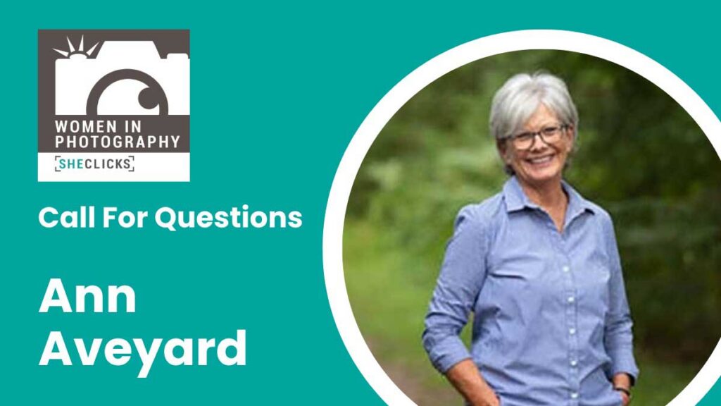 Teal promotional graphic for Women in Photography [SheClicks] featuring the text “Call For Questions” and “Ann Aveyard.” On the right, a circular portrait shows a smiling woman with short gray hair and glasses wearing a blue button-down shirt, standing outdoors against a blurred green background.