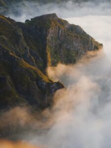 Mountain ridge lit by warm light rising above thick rolling clouds