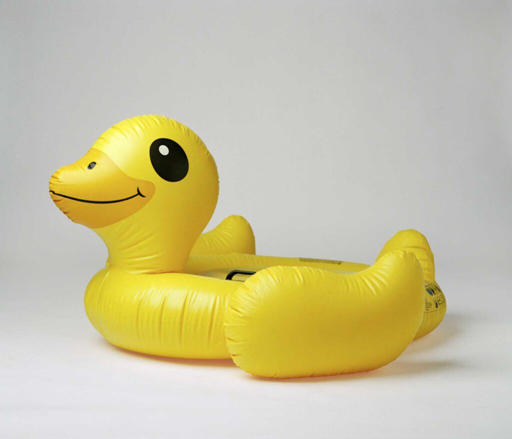 Bright yellow inflatable duck pool float against a plain background.
