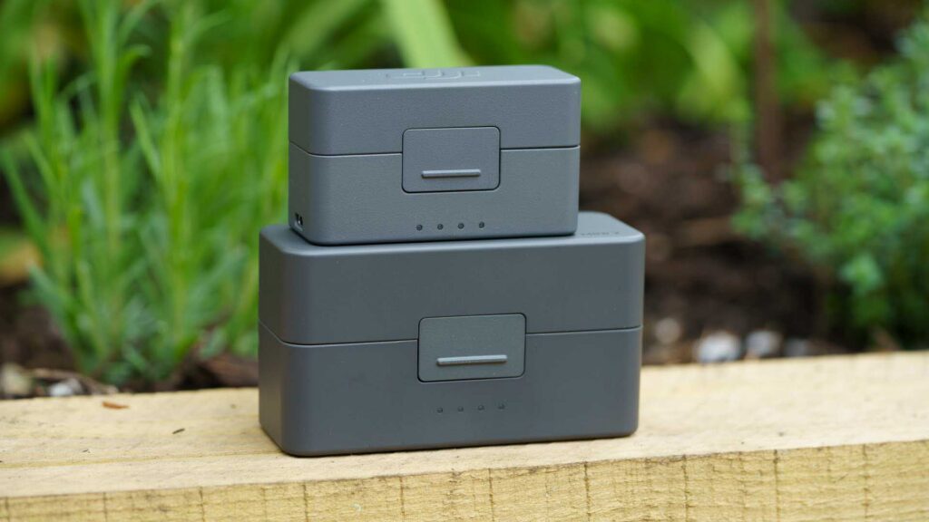 Two stacked charging cases with front latch and LED battery indicators.