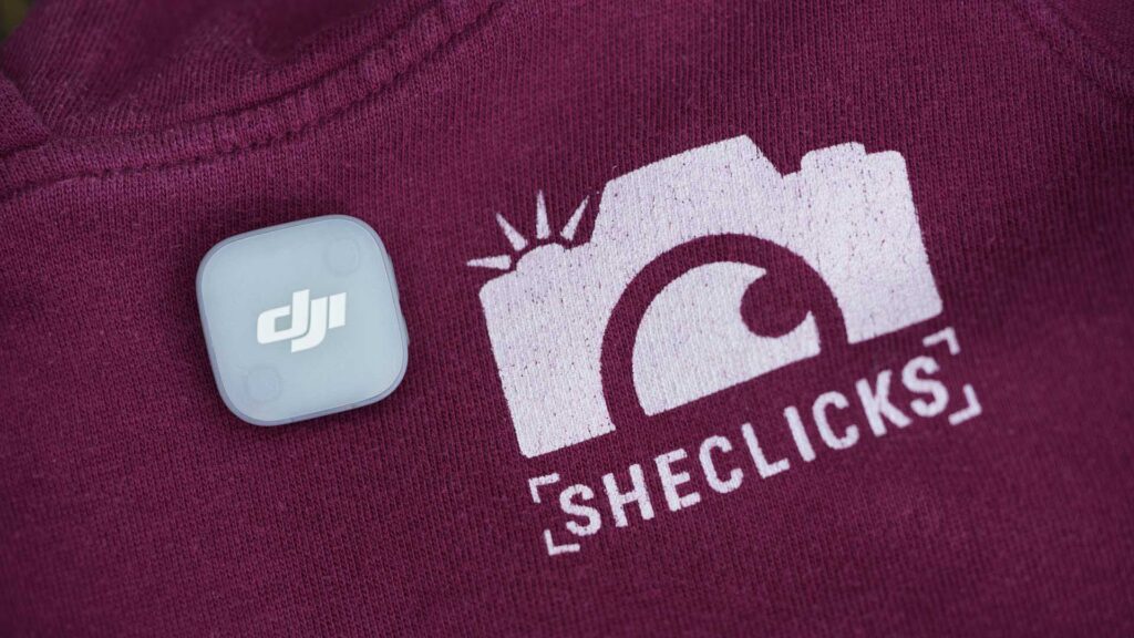 Single transmitter resting on a maroon shirt with “SHECLICKS” logo and camera graphic.