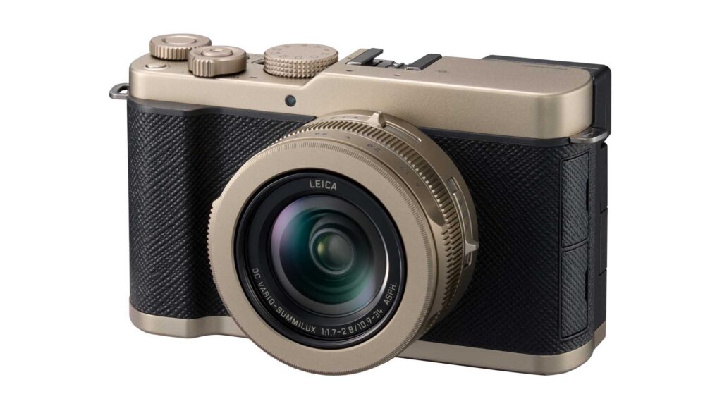 Angled front view of a gold Panasonic Lumix L10 compact camera with a Leica lens against a white background.