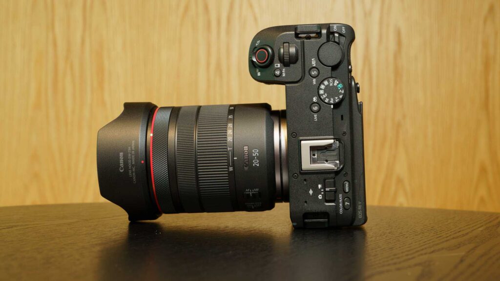 Top-down angled view of the Canon EOS R6 V paired with the RF 20-50MM F4L IS USM PZ lens. The mode dial, hot shoe mount, and recording controls are visible on the camera body.