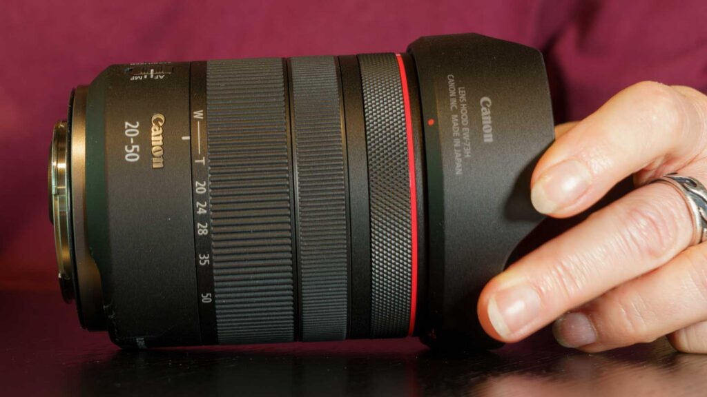 Close-up of the Canon RF 20-50mm F4L IS USM PZ lens with lens hood attached, highlighting the zoom ring and focal length markings.