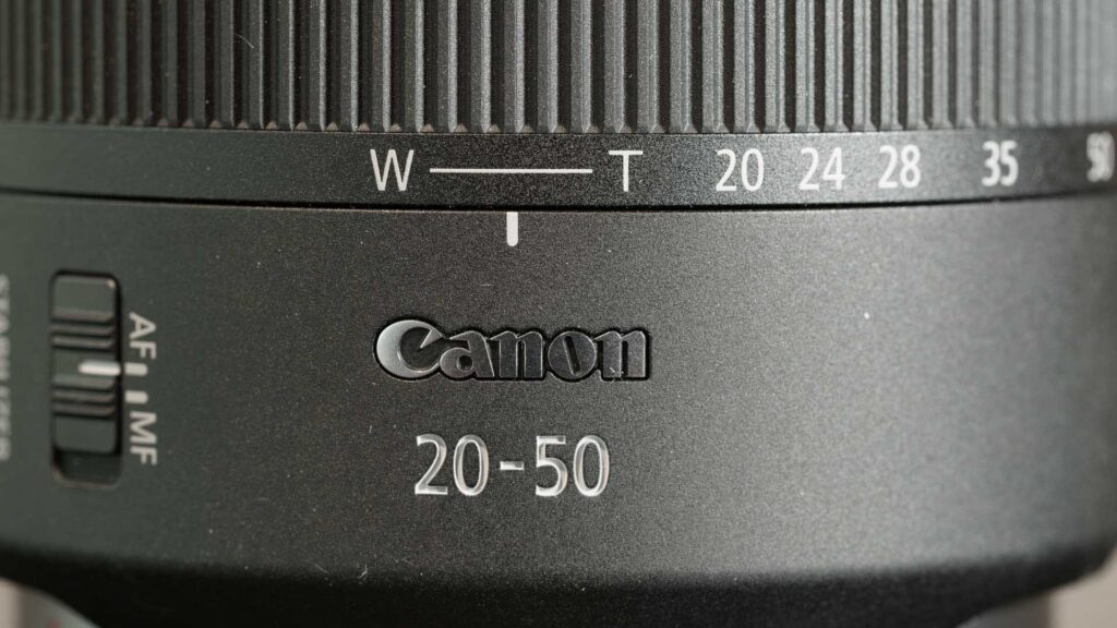 Macro view of the Canon RF 20-50mm F4L IS USM PZ lens showing the focal length scale, W to T scale, and Canon branding.