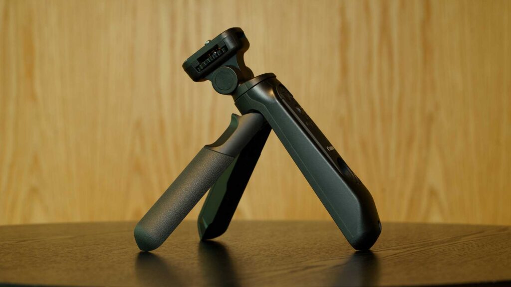 Side view of the Canon HG-200TBR tripod grip standing open on a tabletop against a light wood background.
