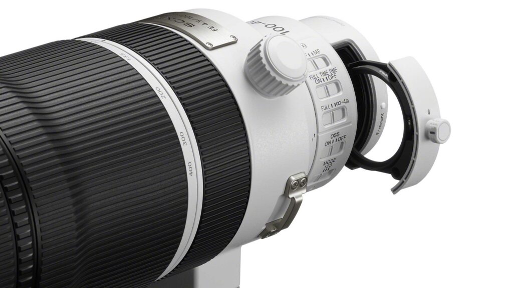 Close-up of the Sony FE 100–400mm F4.5 GM OSS telephoto zoom lens showing focus and stabilization switches, tripod collar, rear drop-in filter and zoom markings.
