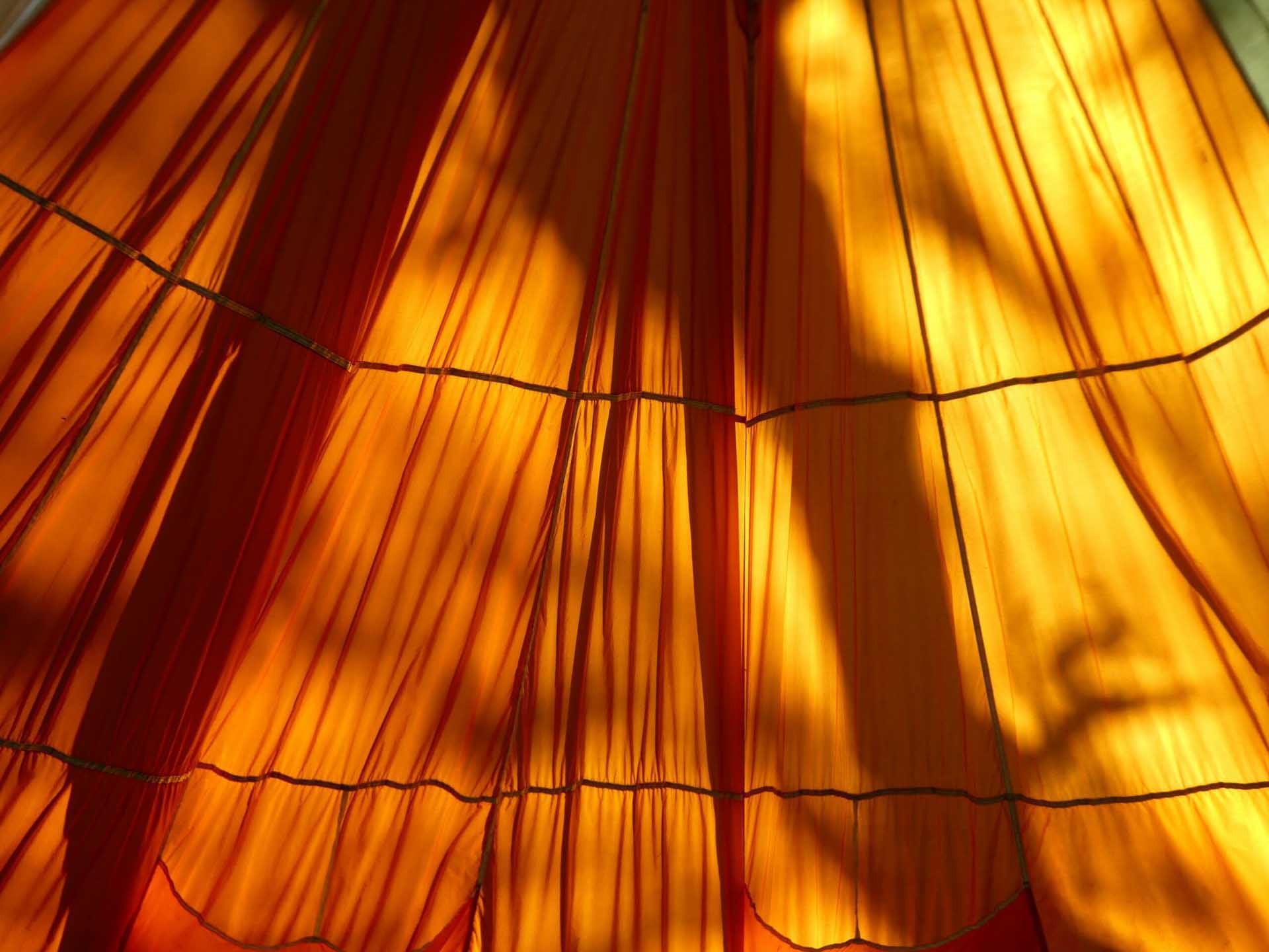 Sunlight filtering through translucent orange fabric creating layered shadows.