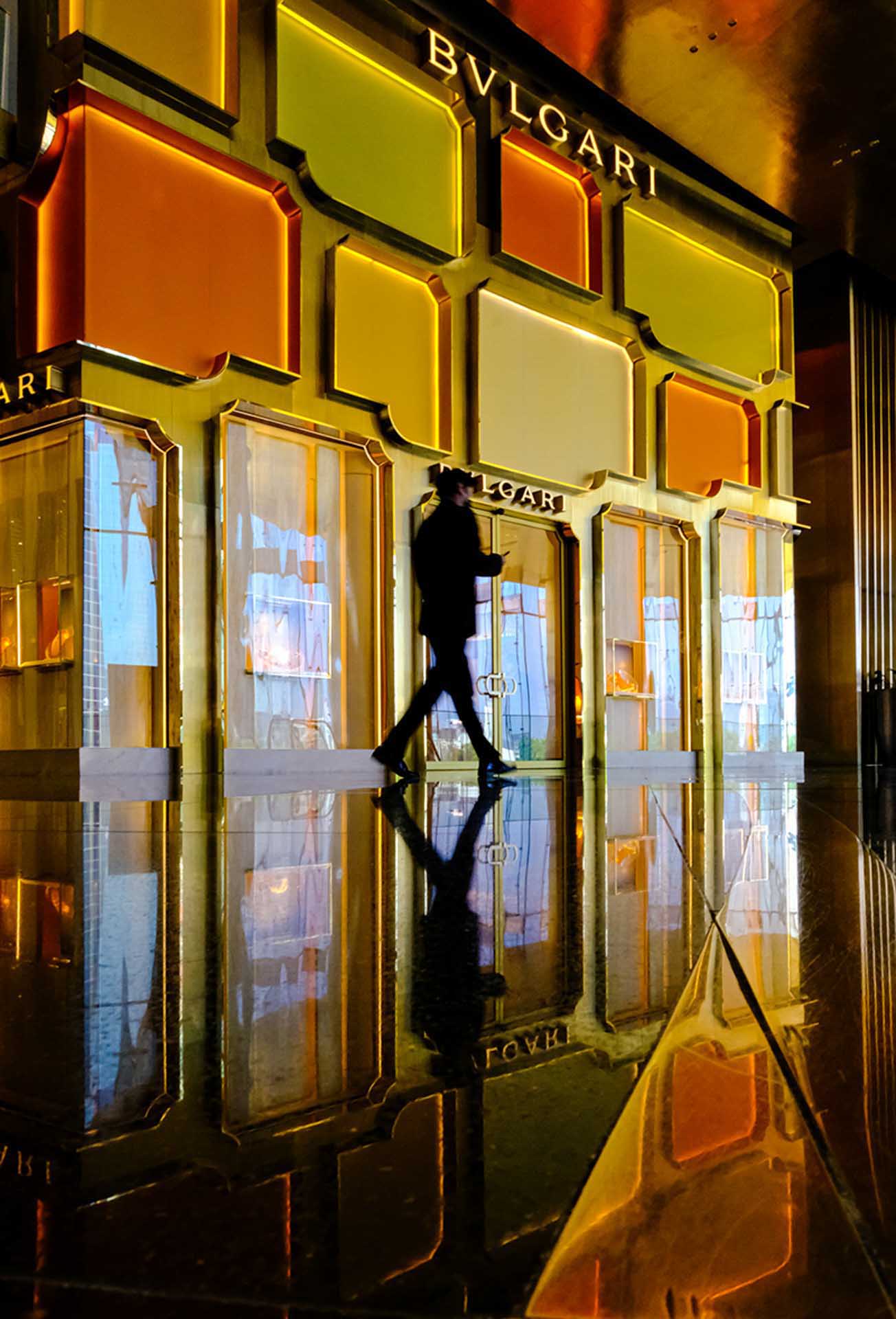 Luxury storefront with illuminated orange and gold panels reflected on a polished floor.