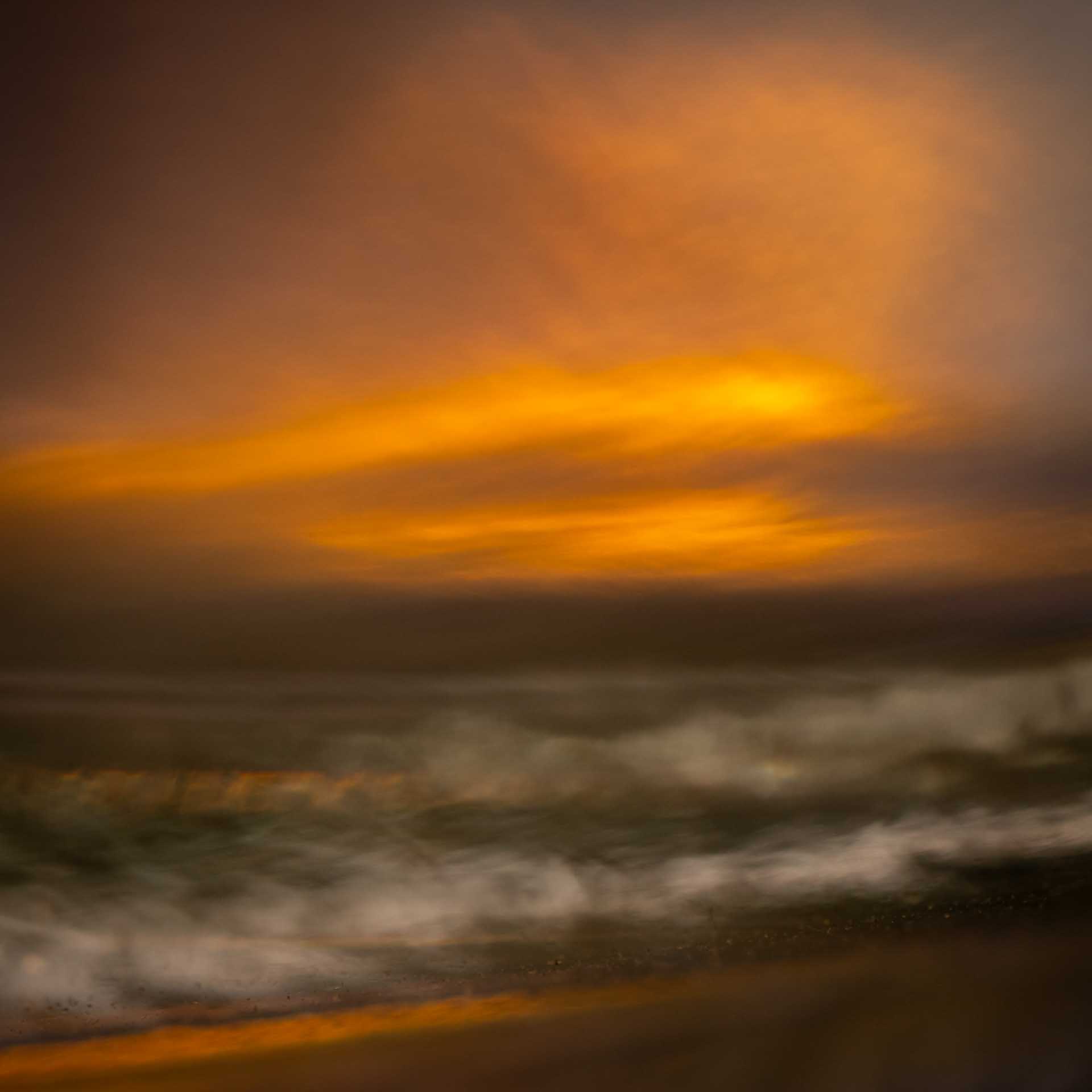 Abstract image that looks like a long-exposure seascape with blurred waves beneath glowing orange clouds.