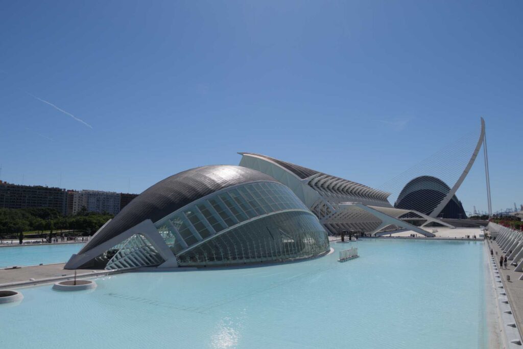 Modern white and glass buildings beside pale blue reflecting pools at Valencia’s City of Arts and Sciences.