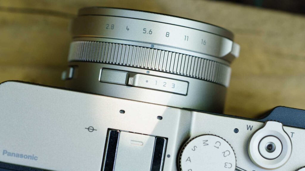 Close-up of the Panasonic Lumix L10 lens barrel and top controls, showing the aperture markings and custom switch.