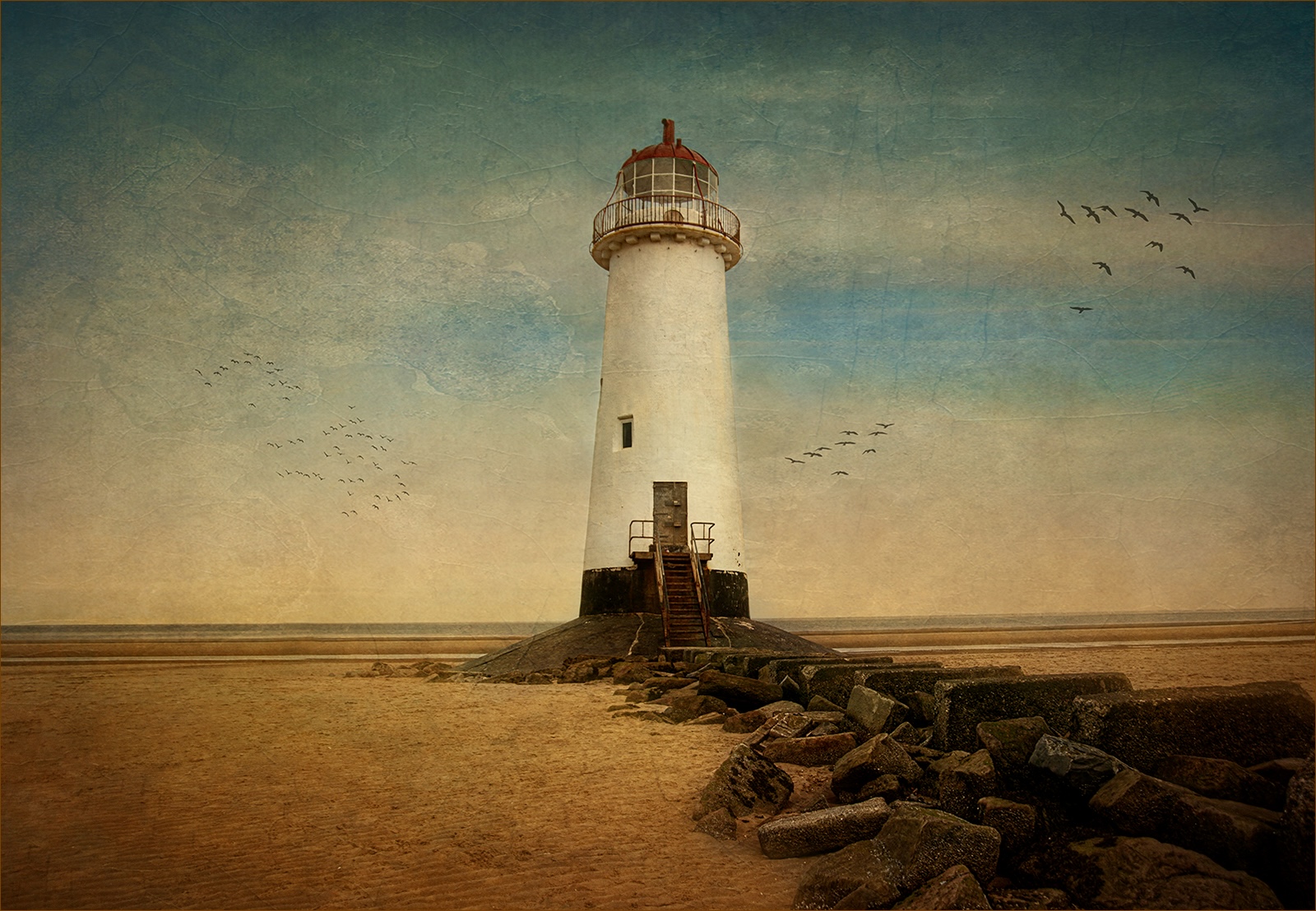 White lighthouse standing on a sandy shoreline at low tide, with flocks of birds flying across a soft blue sky.