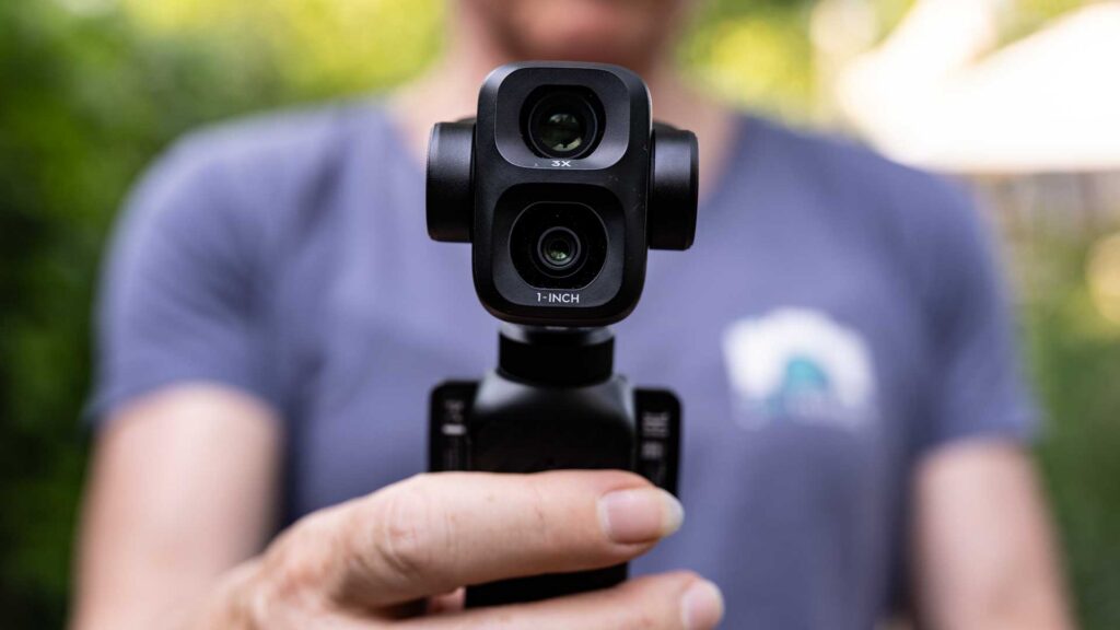 Close-up of the DJI Osmo Pocket 4P dual-lens camera head held towards the viewer, with “3X” and “1-INCH” markings visible.