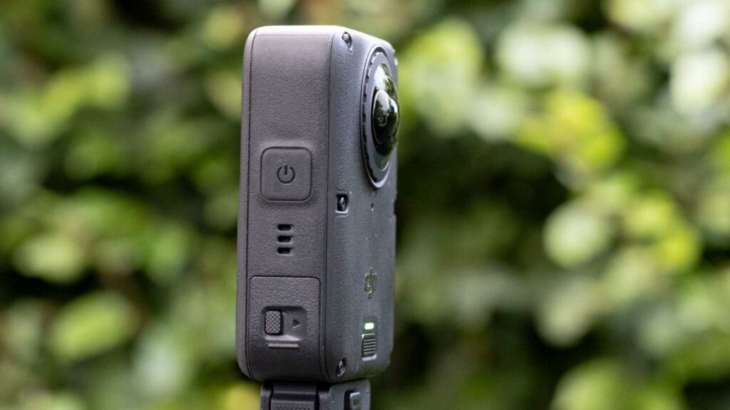 Side view of the DJI Osmo 360 II showing the power button, side controls and protruding fisheye lens.