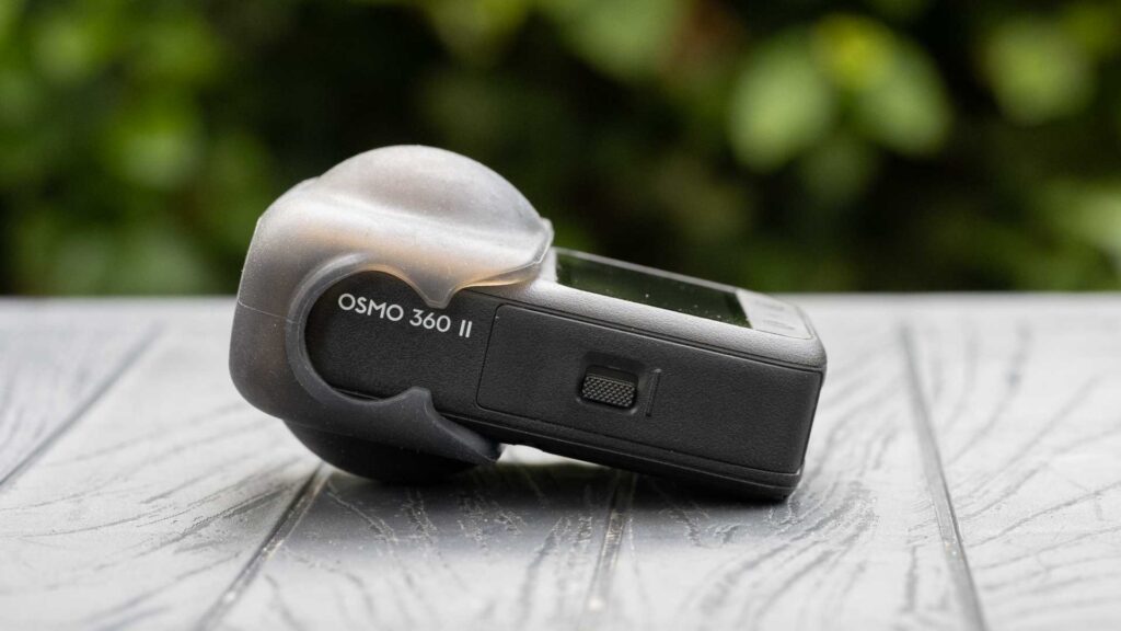 DJI Osmo 360 II lying on its side on a table with a translucent protective cover fitted over one fisheye lens.