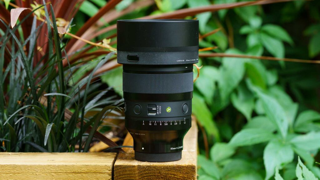 Side view of the Sigma 85mm f/1.2 DG Art with lens hood attached, showing the AF/MF focus switch, function buttons and aperture ring.
