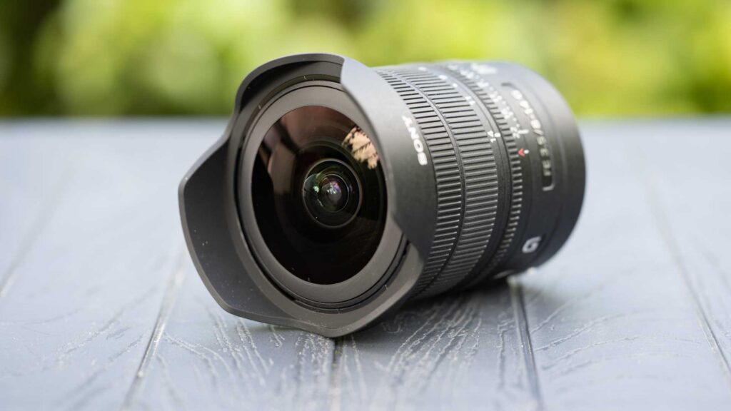 Angled front view of the Sony FE 8-14mm F3.5 Fisheye G showing its large curved front element and built-in petal-shaped hood.