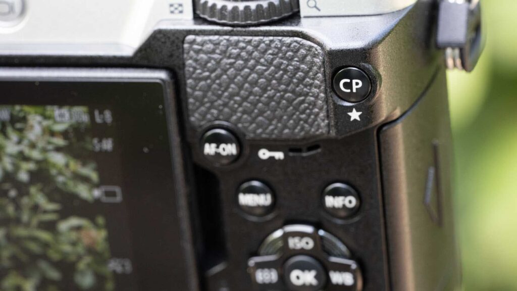 Close-up of the OM System PEN rear grip and controls, highlighting the CP button, AF-ON button, Menu, Info and directional control pad.