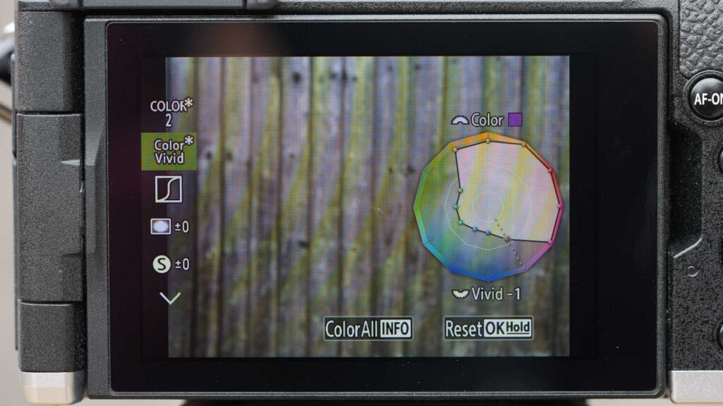 Rear view of an OM System PEN on a tripod, with the screen displaying the Color Vivid profile adjustment and colour wheel.
