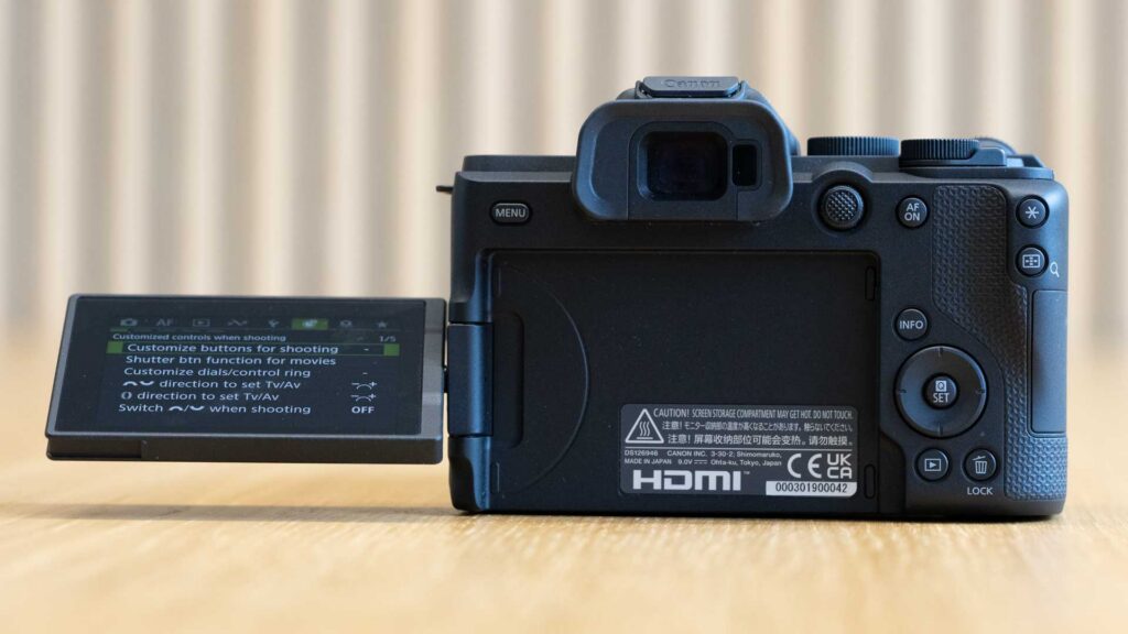 Rear of the Canon EOS R8 Mark II with its vari-angle screen swung left, displaying the customised controls menu with “Customize buttons for shooting” selected.