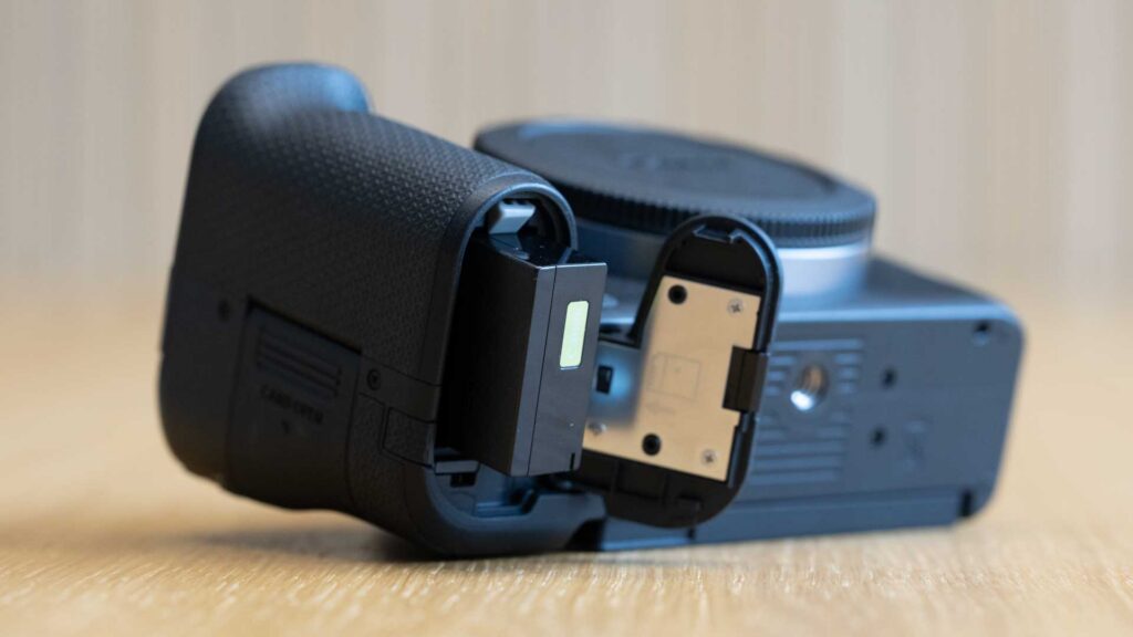 Underside of the Canon EOS R8 Mark II with the battery compartment open and the battery fitted inside.