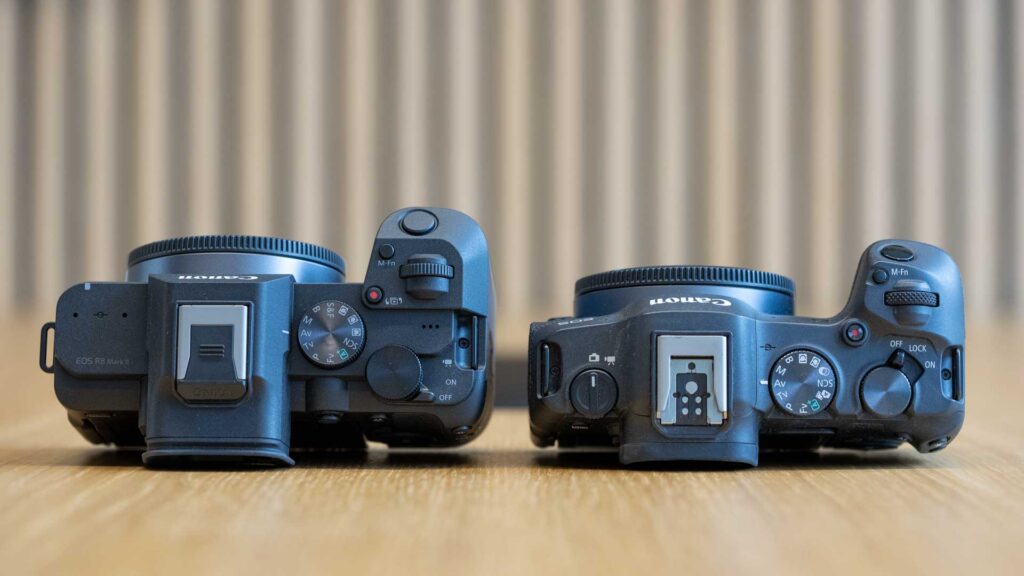 Top-down comparison of the Canon EOS R8 II on the left and EOS R8 on the right, showing their mode dials, hot shoes, control dials and power switches.