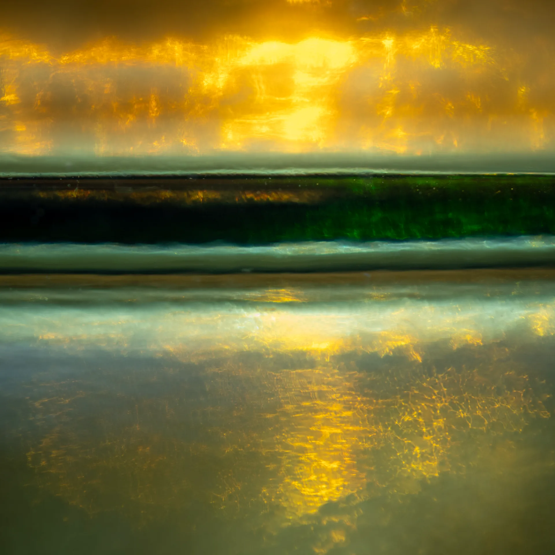 Abstract bands of dark green, pale blue and glowing gold, with warm light reflected across a smooth watery surface.