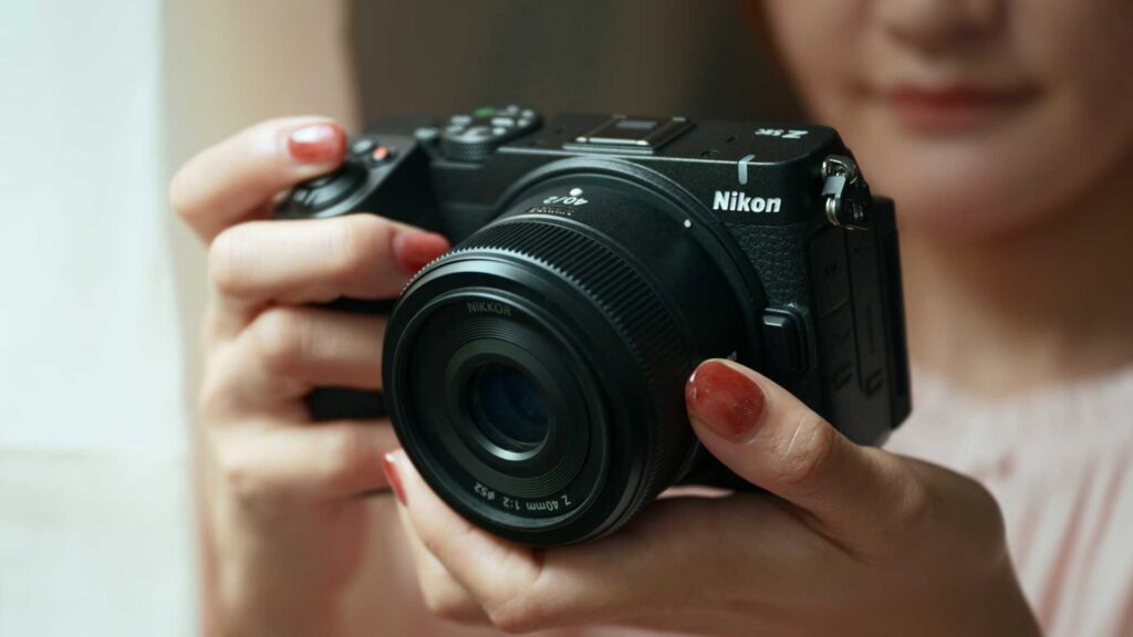 A person holds a black Nikon Z5IIC with a zoom lens, ready to take a photograph.