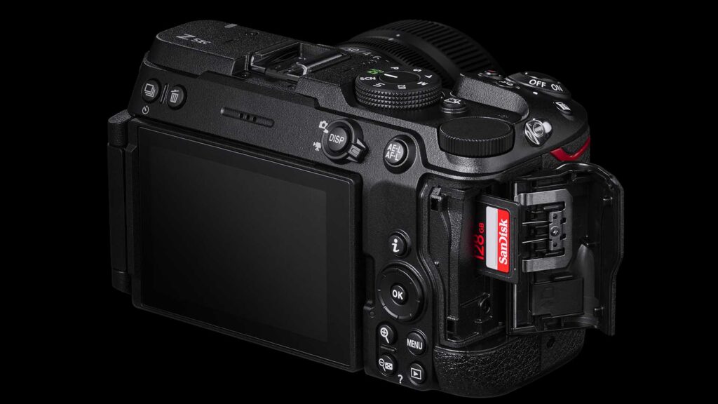 Rear view of a black Nikon Z5IIC with its memory card door open and a SanDisk 128GB SD card inserted.