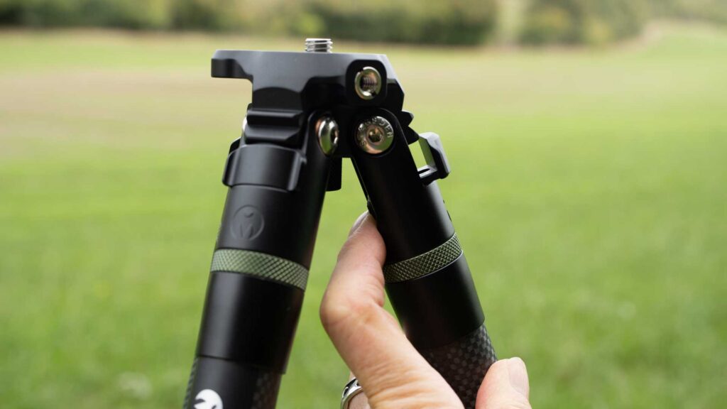 hand holds one tripod leg beside the canopy and its leg-angle adjustment catches.